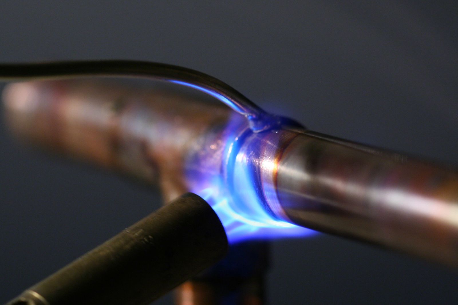 Blue torch flame heating a copper pipe joint for soldering